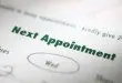 Close-up of a paper with "Next Appointment" in bold text and "Wed" circled below, indicating the scheduled date. Sports Medicine Northwest - West Seattle Chiropractic Clinic