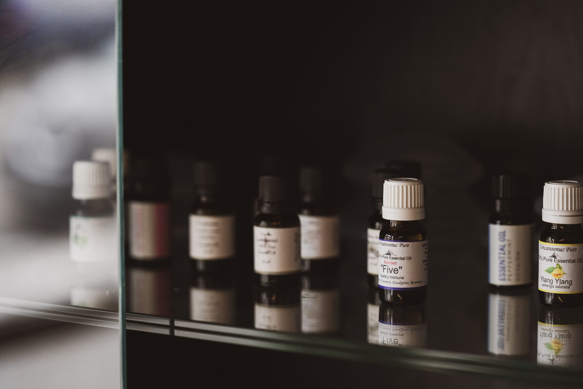 In a serene Seattle Orthopedic Massage Therapy studio, a glass shelf elegantly displays various small bottles of essential oils with labeled caps, infusing the room with calming scents and therapeutic potential. Sports Medicine Northwest - West Seattle Chiropractic Clinic